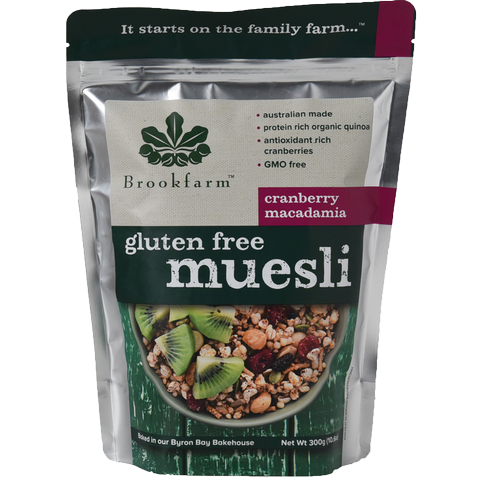Brookfarm gluten free muesli with cranberries and macadamia nuts in a bowl on a wooden surface.