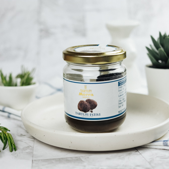 Jar of Tartufalba Summer Truffle in jar showcasing black truffle slices for gourmet cooking and flavor enhancement.