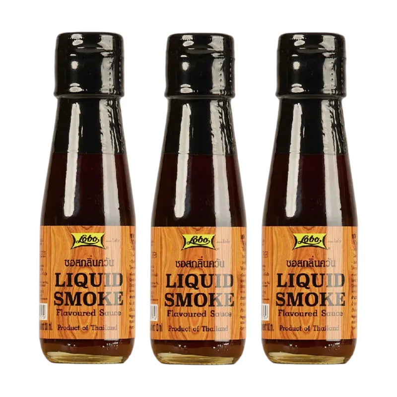 Lobo Liquid Smoke bottle, a clear glass container with black cap, used for adding smoky flavor to dishes in dry grocery aisle.