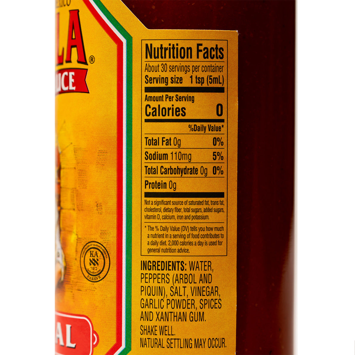 Bottle of Cholula Original Hot Sauce with wooden cap and label, placed on a kitchen counter, ready for use in cooking or as a condiment.