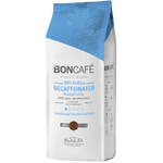 Decaffeinated Boncafe coffee drink in a clear glass cup with a frothy top and coffee beans beside it.