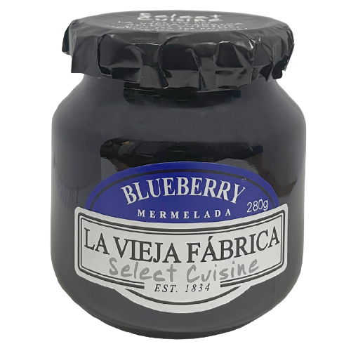 Jar of La Vieja Fabrica Blueberry Jam with fresh blueberries on a rustic wooden table.