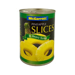 Cans of McGarett pineapple slices in heavy syrup, 565g each, stacked in a grocery store display.
