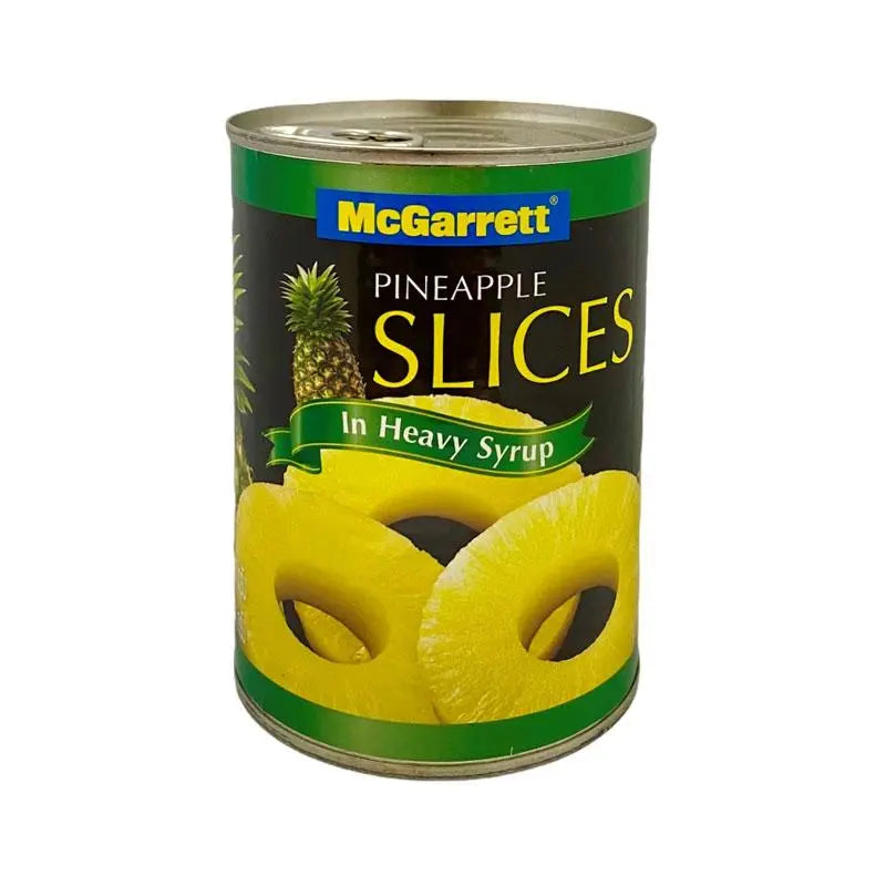 Cans of McGarett pineapple slices in heavy syrup, 565g each, stacked in a grocery store display.
