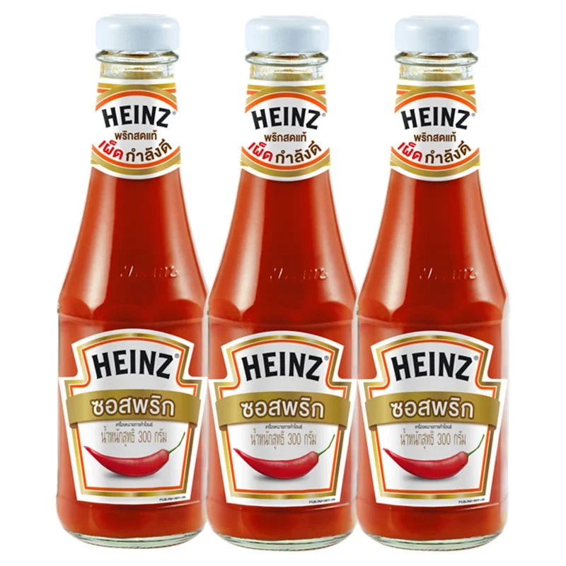 Heinz Chili Sauce 300g bottles, three-pack, in clear glass bottles with red caps, labeled with Heinz branding and chili graphics.