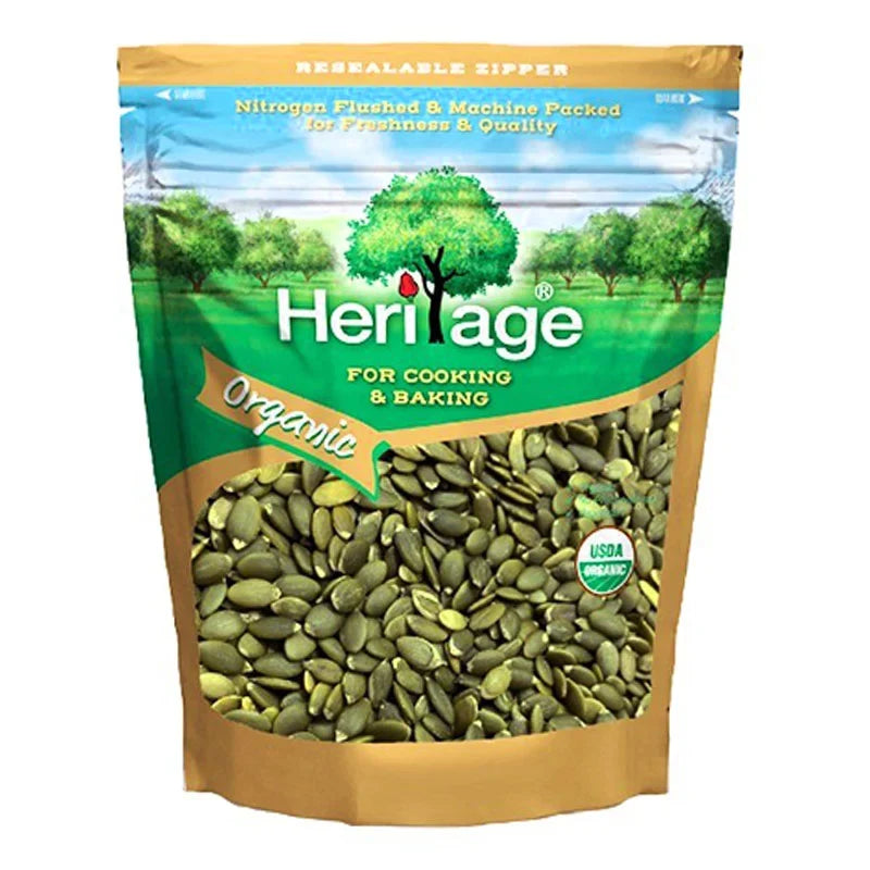 Heritage Organic Raw Pumpkin Seeds 454g in a clear bowl, showing light green and tan pumpkin seeds for healthy snacking or cooking.