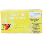 Box of Lipton Yellow Label Tea Bags with tea infuser and steaming cup of brewed tea on a wooden table.