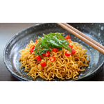 A bowl of Domin Mie Spicy Thai Basil Chicken instant noodles with chopped basil and chili peppers on top.