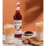 Bottle of MONIN Salted Caramel Syrup in 700ml size, ideal for coffee and desserts, with a caramel-colored label and white cap.