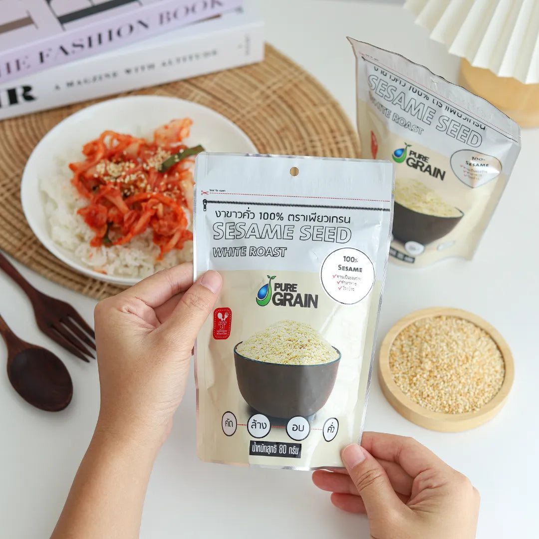 Pure Grain 100% instant roasted white sesame seeds in a 80g pack, ideal for cooking and garnishing in dry grocery recipes.