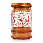 Sacla vegan tomato pesto jar with fresh basil and ripe tomatoes on a white background, ready for pasta or sandwiches.