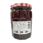 Jar of Bonne Maman strawberry jam with fresh strawberries and a rustic label, 750g size, on a wooden surface.