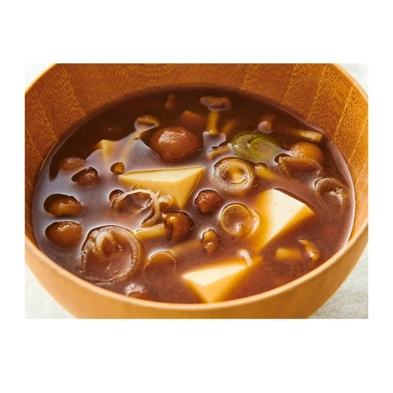 Hanamaruki Akadashi Honba Jikomi Miso made with soybeans, dry grocery product, featuring a bowl of miso paste in a natural setting.