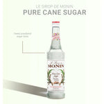 Bottle of MONIN Pure Sugar Cane Syrup 700ml, a clear container with a screw cap, shown in a dry grocery setting.