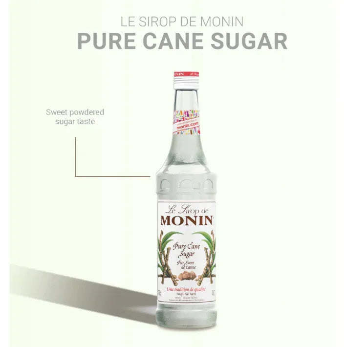 Bottle of MONIN Pure Sugar Cane Syrup 700ml, a clear container with a screw cap, shown in a dry grocery setting.