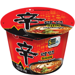 Bowl of Nong Shim Shin Ramyun noodle soup with spicy broth, garnished with green onions and vegetables, in a grocery setting.