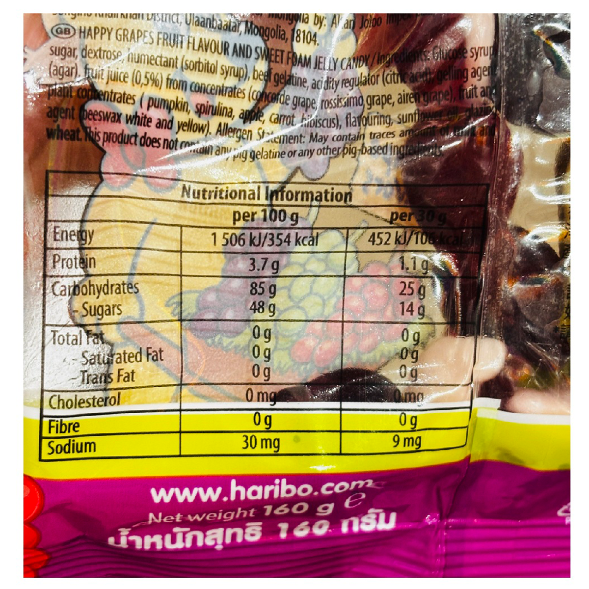 Colorful Haribo Happy Grapes confectionery snacks in a bag, featuring grape-shaped gummy candies in purple and green.