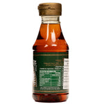 Tate & Lyle Golden Syrup being poured from a jar into a bowl, showcasing the thick, amber syrup in a grocery setting.