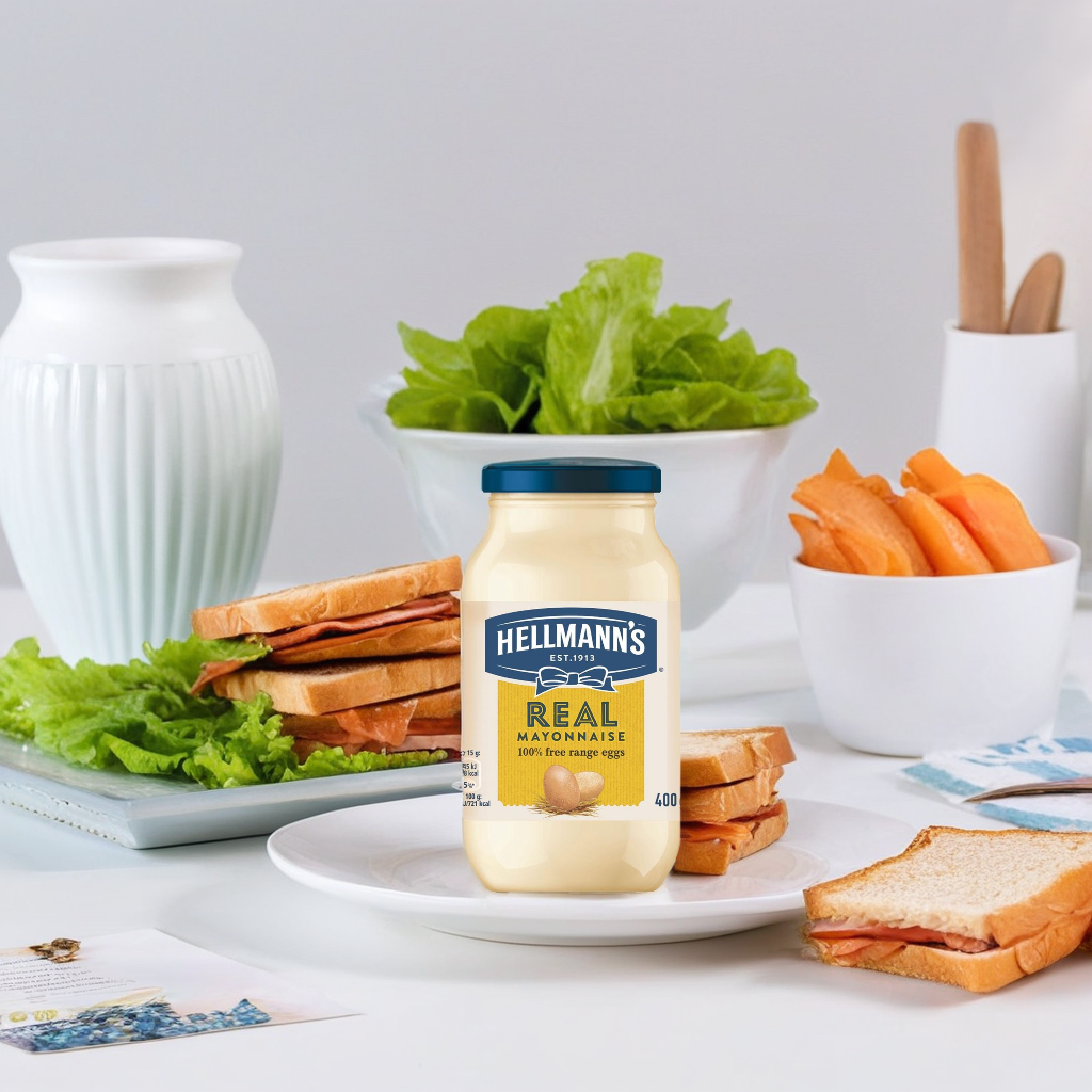 Jar of Hellmann's Real Mayonnaise showing creamy texture and label on a grocery shelf.